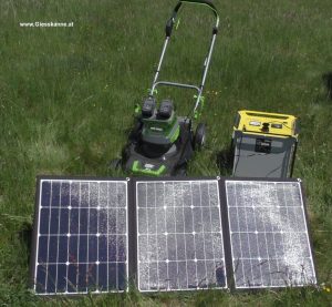 Akkurasenmäher mit Stromspeicher und Photovoltaikmodulen auf der Wiese